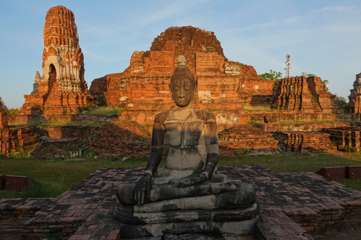 Reste des zentralen Prangs von Wat Mahathat in Ayutthaya, mit Buddha-Statue davor